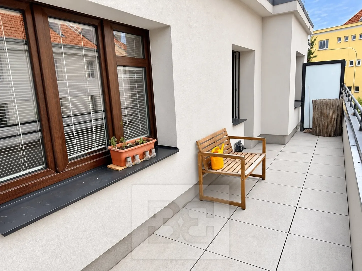Moderní balkon s dřevěnou lavicí a květináčem
