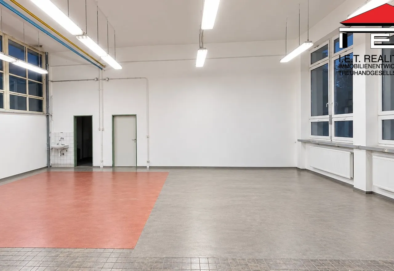 Světlá prázdná průmyslová dílna s červenou podlahou